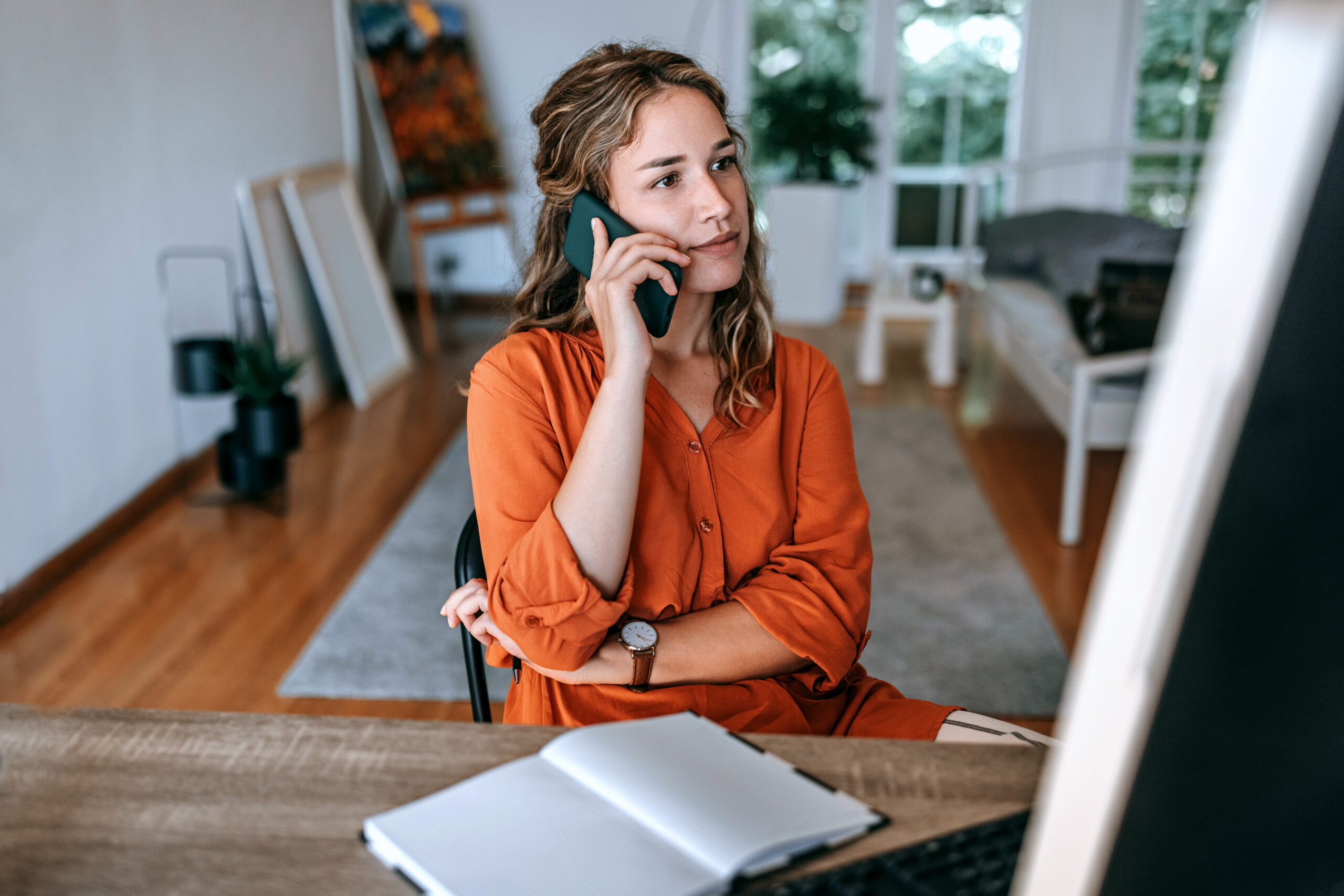 Young Woman Talking On Smart Phone At Home Office